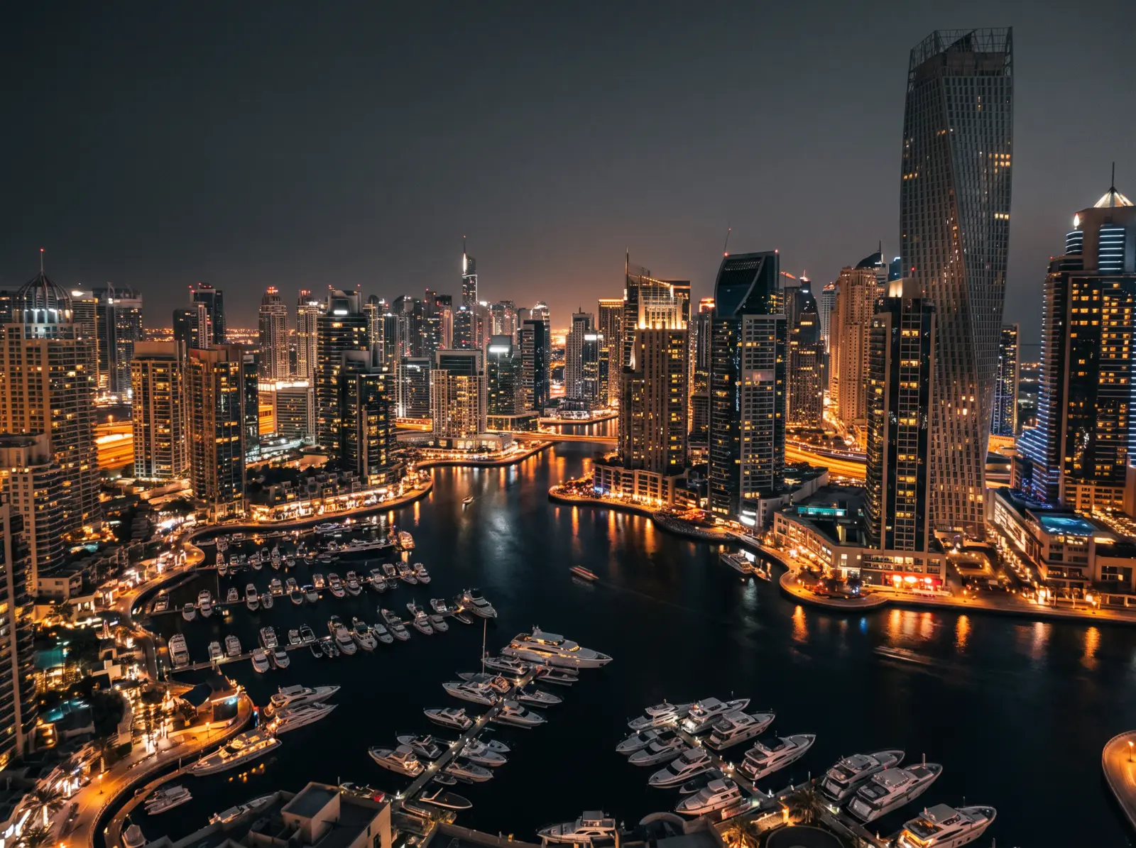 Dubai Marina towers and yacht harbour lit up at night, seen from a high terrace